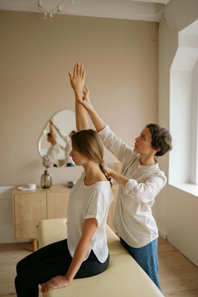Osteopathic treatment — practitioner guiding patient through movement assessment